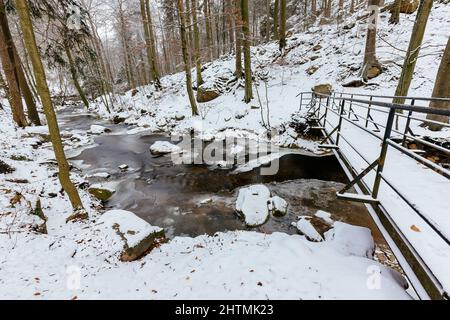 Blick auf den Harz Ilse in Ilsenburg mit Eis und Schnee im Winter Deutschland mit einer Brücke Stockfoto