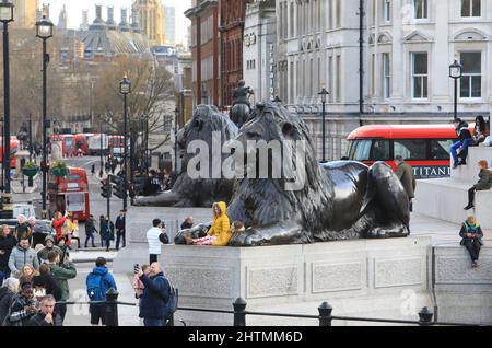 Eine geschäftige Halbzeit im Februar 2022 auf dem Trafalgar Square mit Familien und Freunden, die die Wintersonne im Zentrum von London genießen Stockfoto