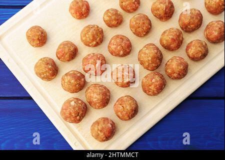Rohe hausgemachte Fleischbällchen auf weißem Kunststoff Schneidebrett Overhead-Ansicht Stockfoto
