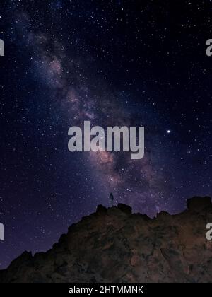 Der Himmel im Dunkeln mit vielen glänzenden Sternen darin und einem Mann, der auf dem Berg steht Stockfoto