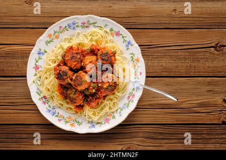 Spaghetti mit Fleischbällchen in Tomatensoße auf Holztisch, Blick von oben Stockfoto