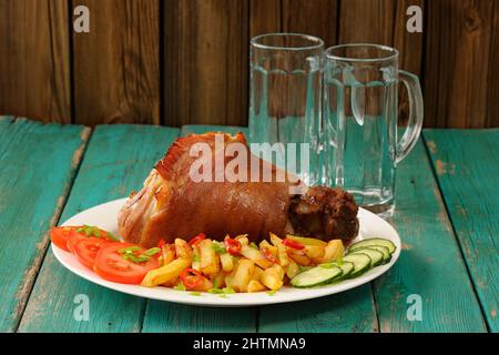 Ganze Eisbein mit pommes Frites, Gurken und Tomaten serviert mit leeren Bierkrügen horizontal Stockfoto