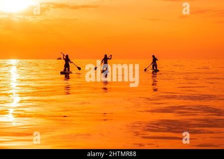 25. Juni 2021. Anapa, Russland. Reisende auf Stand Up Paddle Board am ruhigen Meer mit Sonnenuntergang oder Sonnenaufgang. Mädchen auf Red Paddle supboard und Sonnenuntergang mit Stockfoto