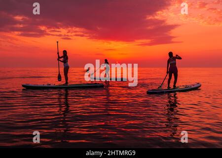 25. Juni 2021. Anapa, Russland. Reisende auf Stand Up Paddle Board am ruhigen Meer mit Sonnenuntergang oder Sonnenaufgang. Mädchen auf Red Paddle supboard und Sonnenuntergang mit Stockfoto