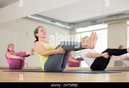 Reife Frauen machen Boot Pose Stockfoto