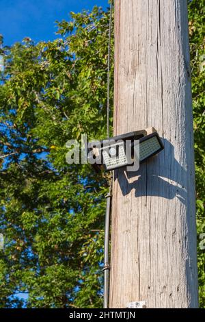 Solarbetriebenes bewegungsaktiviertes Sicherheitslicht an Telefonmast im Wohnhinterhof. Stockfoto