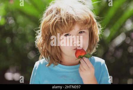 Happy Kleinkind Junge mit frischen Erdbeeren auf grünen Sommer Hintergrund. Stockfoto