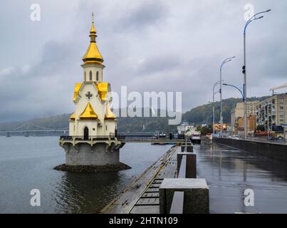 Die orthodoxe Kirche des heiligen Nikolaus des Wundertäters und die Uferpromenade am Dnjepr-Fluss im Bezirk Podil an einem nassen Tag, Kiew, Hauptstadt der Ukraine Stockfoto