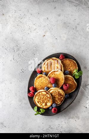 Pfannkuchen in Keramikplatte mit Beeren, Minzblättern, Draufsicht Stockfoto