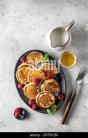 Pfannkuchen in Keramikplatte mit Beeren, Minzblättern, Soße Boote und Gabel, Draufsicht Stockfoto