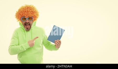 Verrückte Schullehrerin in Perücke und Sonnenbrille zeigen auf blauen Buchdeckel für Kopieplatz, Schulbuch Stockfoto