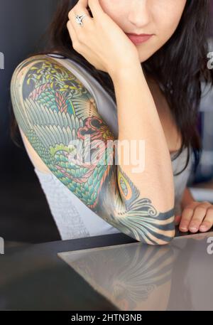 Die Schönheit liegt im Detail. Eine kurze Aufnahme einer jungen Tätowiererin, die ihr Halbärmlentattoo zeigt. Stockfoto