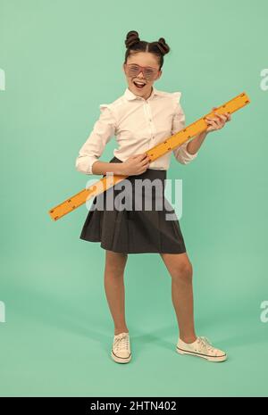 Lächelndes Teenager-Mädchen halten Lineal. Zurück in die Schule. Algebra und Geometrie. Kind studieren Mathematik. Stockfoto