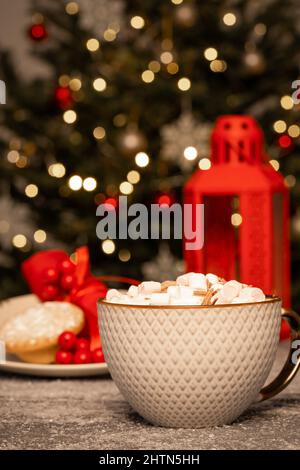 Heiße Schokolade mit Marschwalben vor dem Weihnachtsbaum Stockfoto