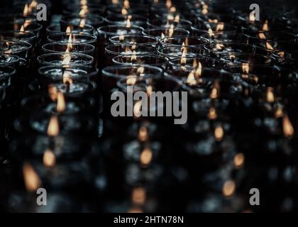 Detail von vielen roten Votivkerzen leuchten im chinesischen Tempel. Reihen von Windlicht-Kerzen im Glas mit geringer Schärfentiefe, verschwommen von Kerzen, Rot ca. Stockfoto