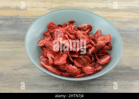 Getrocknete rote Erdbeerscheiben in einer Schüssel mit blauen Zutaten auf dem Tisch einfrieren Stockfoto