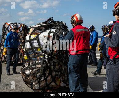 Seeleute der US-Marine sichern sich während einer Nachversorgung auf See an Bord der USS Green Bay, Philippinisches Meer, 15. Februar 2022, Vorräte an der Fluglinie. Die 31. MEU ist an Bord der Schiffe der America Amphibious Ready Group im Einsatzgebiet der 7. Flotten tätig, um die Interoperabilität mit Verbündeten und Partnern zu verbessern und als eine ready Reaktion zur Verteidigung von Frieden und Stabilität in der Indo-Pazifik-Region zu dienen. (USA Marine Corps Foto von Lance CPL. Yvonne Iwae) Stockfoto