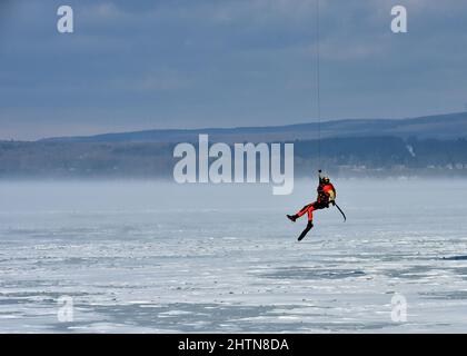 Petty Officer 3. Class James Lowen, ein Rettungsschwimmer der Air Station Traverse City, bereitet sich auf den Sprung auf einen gefrorenen Lake Michigan während einer großen Eisrettungsübung am 26. Februar 2022 in der Petoskey Municipal Marina vor. Die Übung, bei der der Absturz eines Pendlerflugzeugs in der Little Traverse Bay simuliert wurde, zog mehr als 100 Ersthelfer und Küstenwache-Mitglieder aus dem gesamten Norden von Michigan an. Foto der US-Küstenwache vom Chief Petty Officer John Masson. Stockfoto