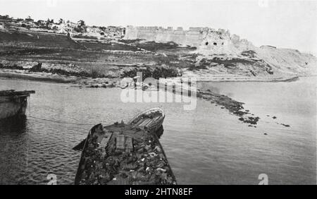 Sedd-el-Bahr Fort und Dorf vom SS-Fluss Clyde aus gesehen, 25. April 1915, während der Landung am Kap Helles, Schlacht von Gallipoli. Das Boot im Vordergrund enthält Tote der Royal Munster Fusiliers und des Hampshire Regiment, die bei dem Versuch, an Land zu kommen, getötet wurden. Stockfoto