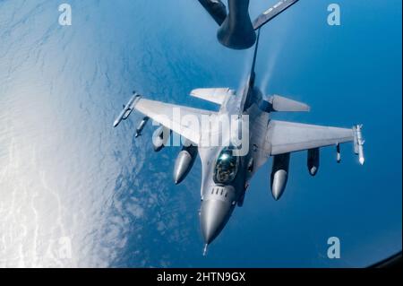Ein Kampffalcon der US-Luftwaffe F-16, der dem 332d Air Expeditionary Wing zugewiesen wurde, nähert sich einem US-Luftwaffe-Stratotanker KC-135, der der 28. Expeditionary Air Betankungsschwadron zugewiesen wurde, um Lufttanken über dem Arabischen Golf durchzuführen, 26. Februar 2022. Die 28. EARS, die bei der US Air Forces Central eingesetzt wurden, betanken mit sechs US-Kampfflugzeugen aus der Luft, um eine Übung mit einem Partnerland zu unterstützen. (USA Foto der Luftwaffe von Staff Sgt. Jerreht Harris) Stockfoto