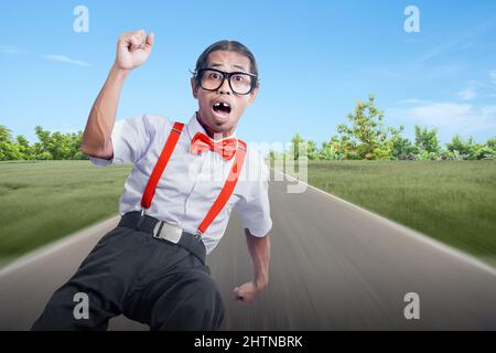 Asiatischer Nerd mit hässlichem Gesicht auf der Straße mit blauem Himmel Hintergrund Stockfoto