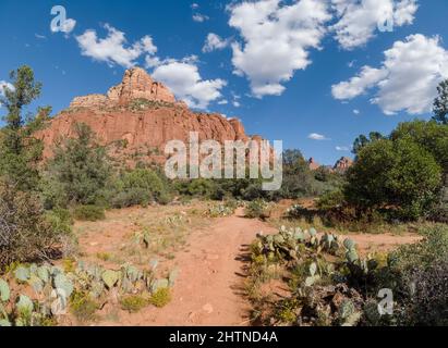 Unbefestigte Wanderweg durch die Wüste führt zu einer großen Felsformation. Stockfoto