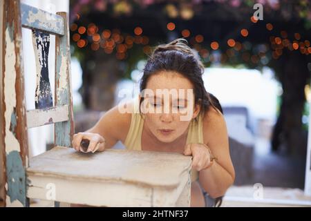 Antiquitäten herunterzuschleifen macht Spaß. Eine junge Frau, die einen antiken Stuhl herunterschleift. Stockfoto