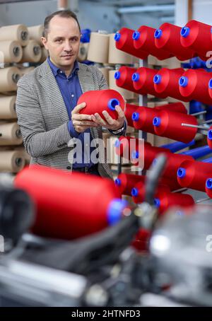 01. März 2022, Sachsen, Flöha: Nico Teutsch, Geschäftsführer, steht im Wickelraum der OTEX Textilveredlung GmbH. Das Unternehmen mit 90 Mitarbeitern stellt Spezialgarne für Medizinprodukte und technische Textilien her. Als 2016 nach einem Nachfolger für das Werk gesucht wurde, übernahm die Thüringer Bauerfeind AG, Hersteller von medizinischen Hilfsmitteln wie Verbänden, Orthesen oder orthopädischen Einlagen, einfach ihren Lieferanten selbst. Die Zahl der Beschäftigten stieg, und nun gehören auch mehrere Rumänen und Südamerikaner zur Belegschaft. Am Mittwoch (02.03.2022), die Vereinigung der Ost-Ge Stockfoto