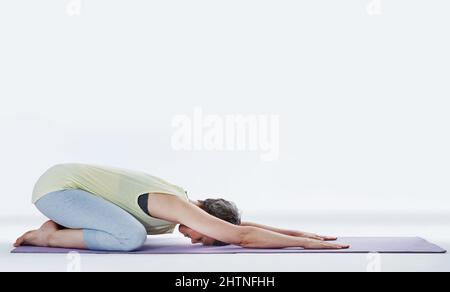 Stellen Sie sicher, dass Sie sich vor dem Training aufwärmen. Ganzkörperaufnahme einer attraktiven Frau, die sich vor dem Yoga dehnt. Stockfoto
