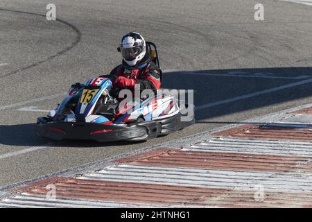 Mann im Helm fährt tagsüber Go-Kart auf Kartbahn Stockfoto