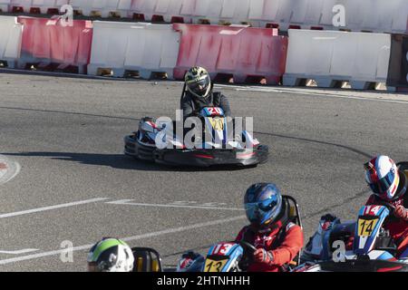 Blick auf vier Männer im Helm, die tagsüber Go-Kart auf der Kartbahn fahren Stockfoto