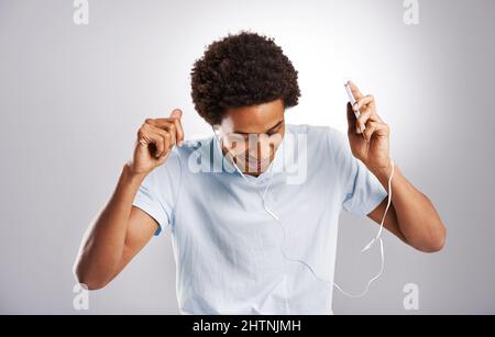 Musik ist ein sicheres High. Studioaufnahme eines jungen Mannes, der Musik auf seinem Handy hört. Stockfoto