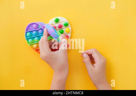 Kinderhände Nehmen Sie die vorbereitete Schokolade mit eigenen Händen aus der popit-Silikonform heraus. Verwenden Sie das beliebte Pop-it-Spielzeug als Schokolade. DIY CO Stockfoto