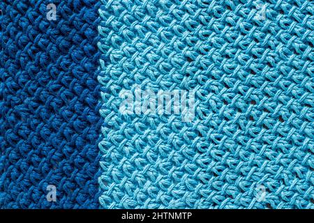 Stück aus zweifarbigem blauem Strickstoff, Hintergrund oder Textur. Strickgarn handgefertigt. Stockfoto