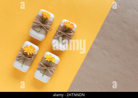 Handgemachte Naturseife, verziert mit Bastelpapier, Geißeln und orangefarbenen Ringelblumenblüten. Bio-Kosmetik-Konzept. Draufsicht Flat Lay-Vorlage für Stockfoto