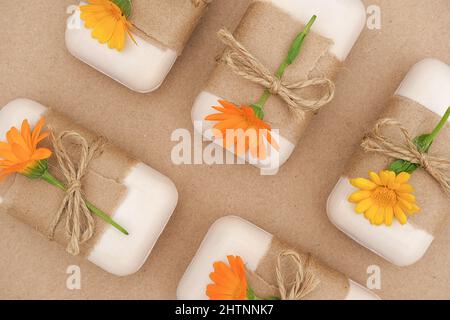 Handgemachte Naturseife, verziert mit Bastelpapier, Geißeln und orangefarbenen Ringelblumenblüten. Bio-Kosmetik-Konzept. Draufsicht Flat Lay-Vorlage für Stockfoto