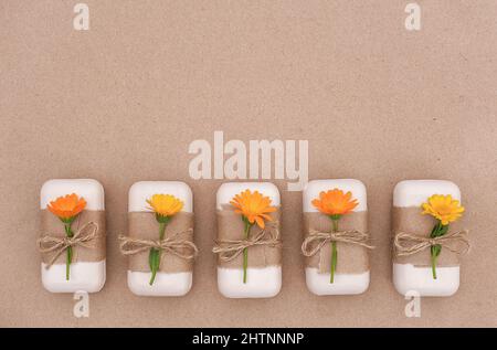 Handgemachte Naturseife, verziert mit Bastelpapier, Geißeln und orangefarbenen Ringelblumenblüten. Bio-Kosmetik-Konzept. Draufsicht Flat Lay-Vorlage für Stockfoto