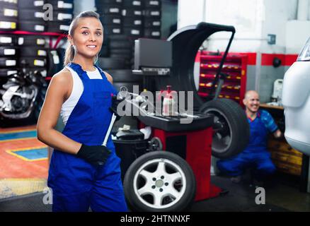 Mechanikerin, die an der neuen Reifenmontage in der Servicestelle arbeitet Stockfoto