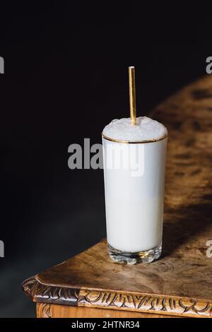 Ramos Gin Fizz Milchshake-Weißschaum aus goldfarbenem Hochglas mit goldenem Trinkhalm Stockfoto