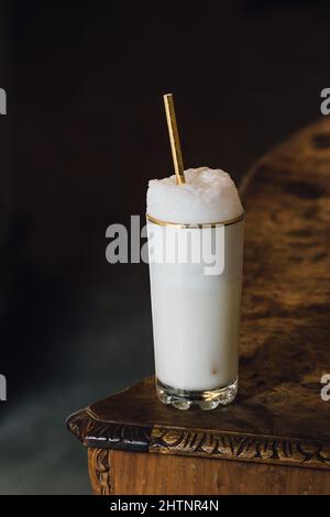 Ramos Gin Fizz Milchshake-Weißschaum aus goldfarbenem Hochglas mit goldenem Trinkhalm Stockfoto