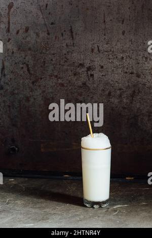 Ramos Gin Fizz Milchshake-Weißschaum aus goldfarbenem Hochglas mit goldenem Trinkhalm Stockfoto