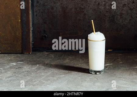 Ramos Gin Fizz Milchshake-Weißschaum aus goldfarbenem Hochglas mit goldenem Trinkhalm Stockfoto