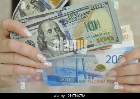 Weibliche Hände halten russische Rubel und Dollar in bar. Finanzkrise. Stockfoto