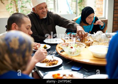 Essen bringt Familie zusammen. Aufnahme einer muslimischen Familie, die zusammen isst. Stockfoto