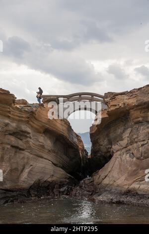 Eine Asiatin liest eine Karte am Rande einer Brücke im Yehliu Geopark, New Taipei City, Taiwan, ROC Stockfoto