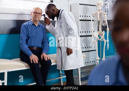 Spezialist Otoologe Mann Arzt Überprüfung Ohrenentzündung mit medizinischen Otoskop Diskussion der Gesundheitsversorgung mit Rentner alten Patienten während der Krankheit Beratung im Krankenhaus. Medizinkonzept Stockfoto