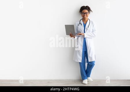 Lächelnde schwarze Ärztin, die mit einem Laptop hält Stockfoto