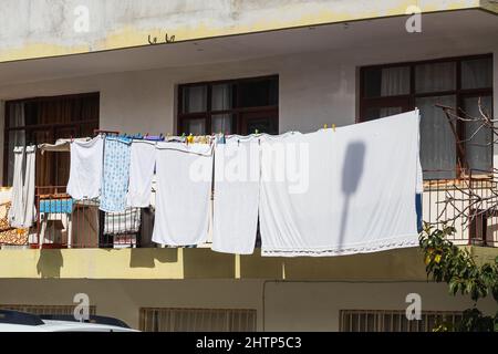 Nahaufnahme an einem Seil, frisch gewaschene weiße Bettwäsche, ein Handtuch, Friseurhemden und andere Dinge werden aufgehängt Stockfoto