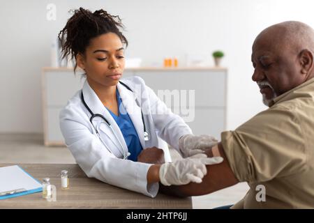 Schwarzer Reifer Mann, Der Geimpft Wird, Arzt, Der Selbstklebende Bandage Aufträgt Stockfoto