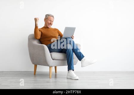 Reifer Mann mit Laptop feiert Erfolg Schütteln Fäuste Stockfoto